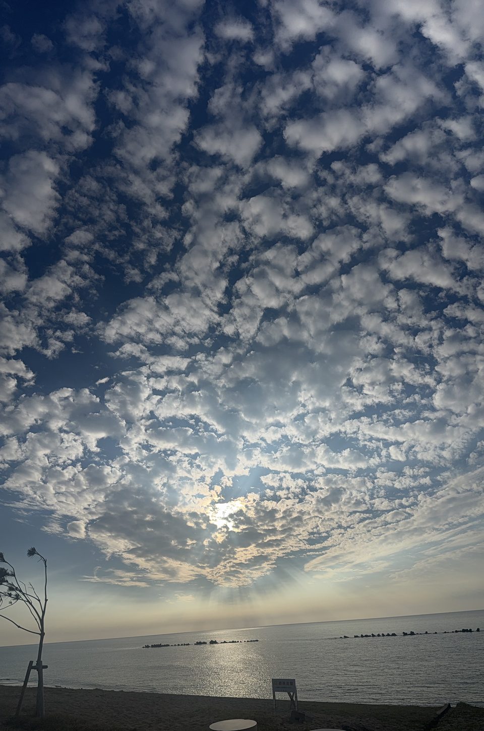 石川県の海辺。うろこ雲の隙間から光が差す夕方の空