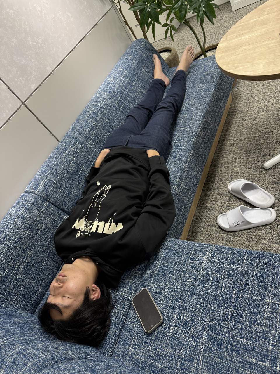 デスク近くのソファーで、ポケットに手を入れたまま眠る同僚
