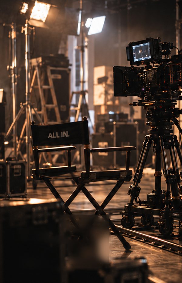 収録現場に置かれた、ALL IN.と書かれたディレクターチェアとカメラ